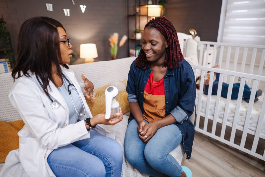 An nurse sitting in a mother's nursery Defining hospital-grade breast pumps to the mother while holding the breast pump